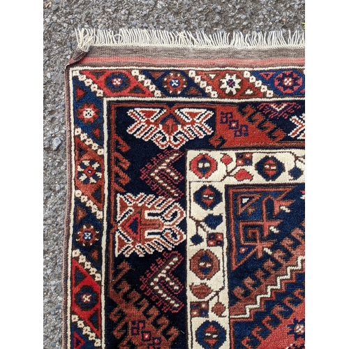 544 - A Turkish rug, the symmetrical blue abstract design on a red background with a central motif having ... 