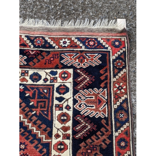 544 - A Turkish rug, the symmetrical blue abstract design on a red background with a central motif having ... 