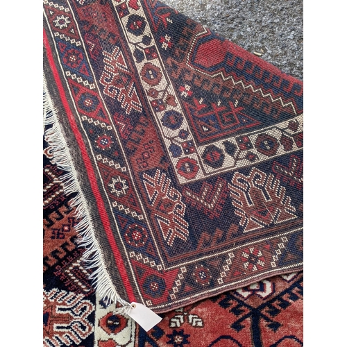 544 - A Turkish rug, the symmetrical blue abstract design on a red background with a central motif having ... 