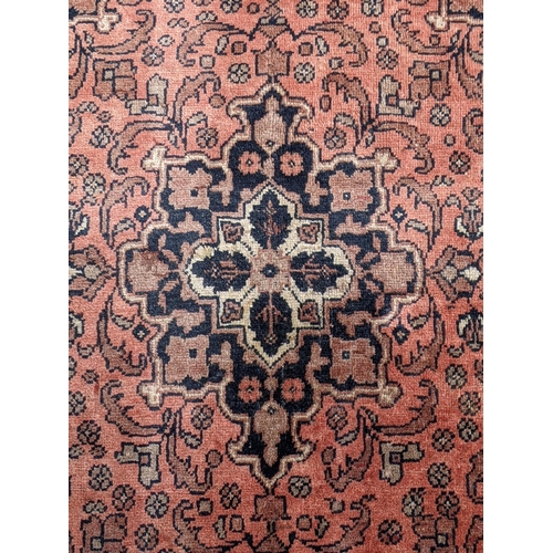 545 - An Iranian Ardakan rug decorated with stylized flowers on a red background with a central medallion ... 