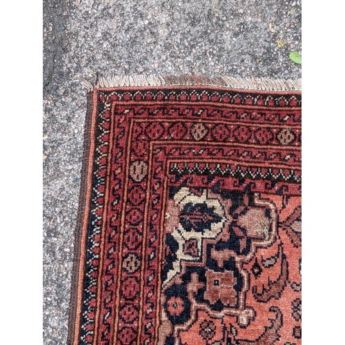 545 - An Iranian Ardakan rug decorated with stylized flowers on a red background with a central medallion ... 