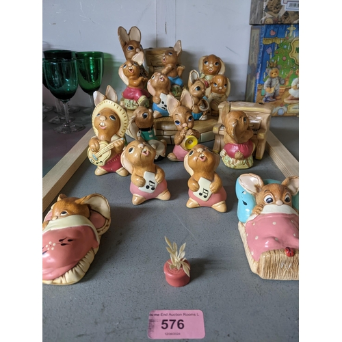 576 - A gathering of Pendelfin plaster rabbit figurines on a display stand to include a piano player and p... 