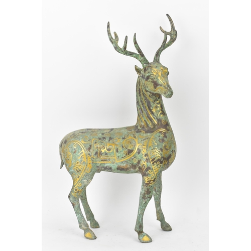 628 - A Chinese patinated bronzed model of a stag, decorated with gilt scroll designs and character marks,... 