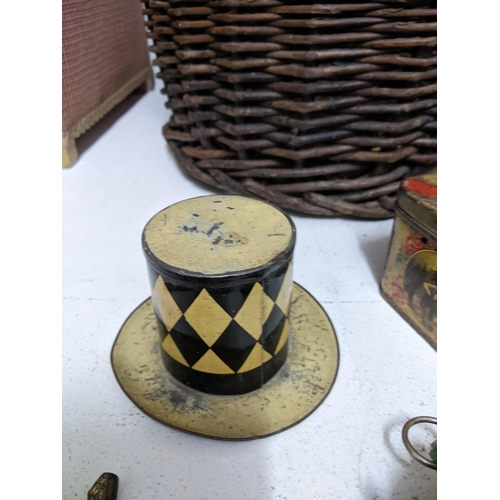 299 - Two wicker baskets containing various vintage tins, one in the form of a top hat, a wooden handled d... 