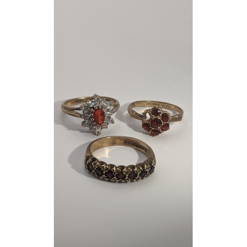 155 - Three 9ct gold ladies rings to include two set with garnets, and the other set with paste stones, to... 