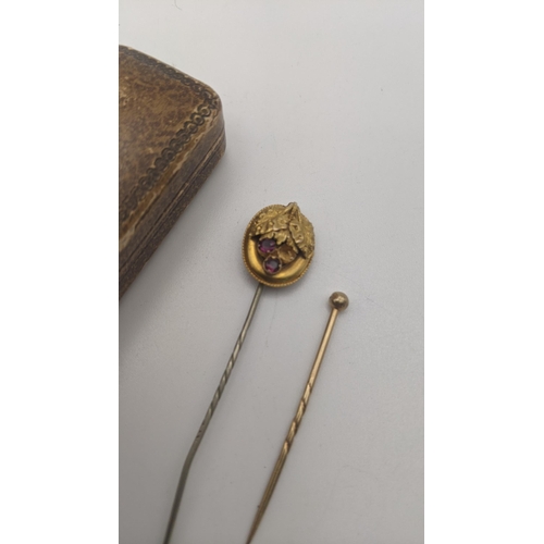 159 - Two gold stick pins to include one set with amethyst coloured stones with a later pin, and one other... 