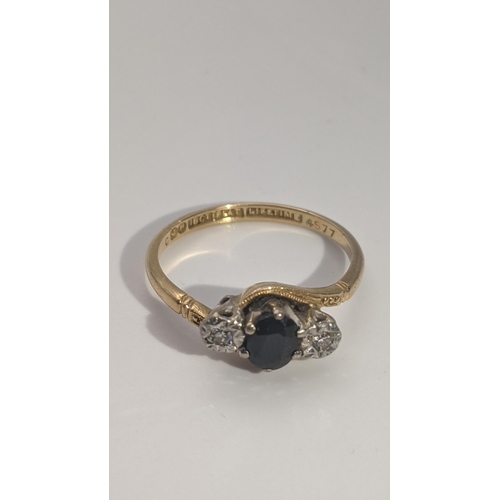 163 - An 18ct gold and platinum crossover ring set with a sapphire flanked by a pair of illusion set diamo... 