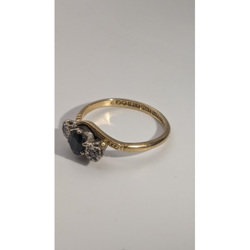 163 - An 18ct gold and platinum crossover ring set with a sapphire flanked by a pair of illusion set diamo... 