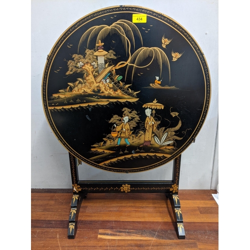 434 - An Oriental style modern lacquered circular folding table decorated with figures and exotic birds an... 