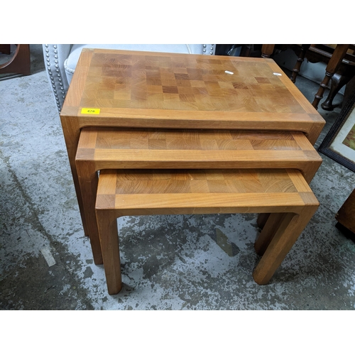 476 - A Danish teak nest of three tables with inlaid chequerboard pattern to the top, the largest 45cm x 6... 