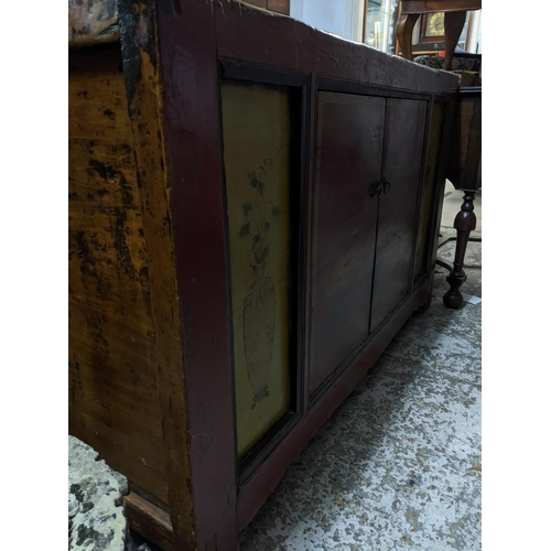 503 - An Asian hardwood side cabinet, twin painted doors decorated with a plant and a bowl of fruit on sta... 