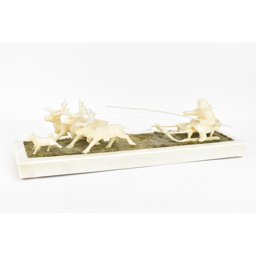 188 - An Inuit carved marine ivory figure group depicting a figure seated on a sleigh being drawn by three... 