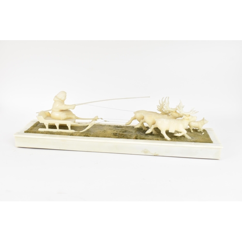 188 - An Inuit carved marine ivory figure group depicting a figure seated on a sleigh being drawn by three... 