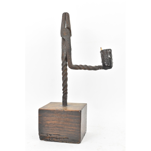 191 - An 18th century wrought iron rush-light holder, with a candle socket arm raised on an oak base, 25cm... 