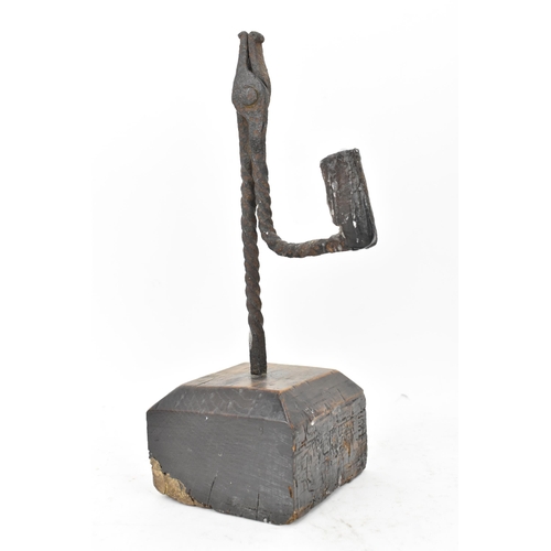 192 - An 18th century wrought iron rush-light holder, with a candle socket arm raised on an oak base, 26cm... 