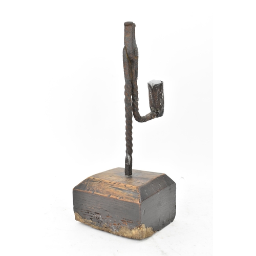 192 - An 18th century wrought iron rush-light holder, with a candle socket arm raised on an oak base, 26cm... 