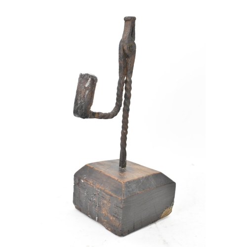 192 - An 18th century wrought iron rush-light holder, with a candle socket arm raised on an oak base, 26cm... 