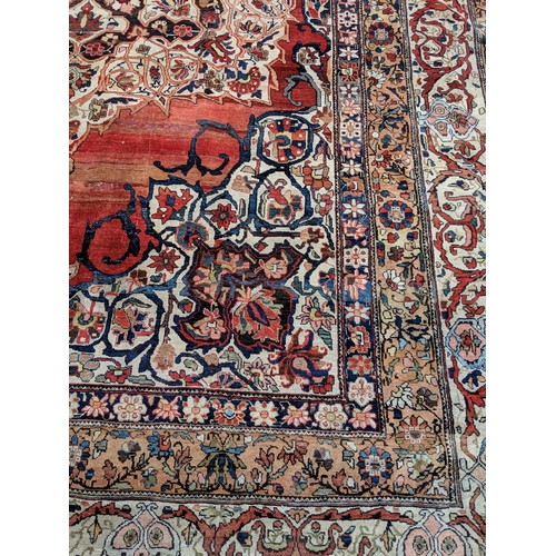 244 - A Persian Heriz hand woven carpet, having a central medallion on a red ground, framed by ivory colou... 