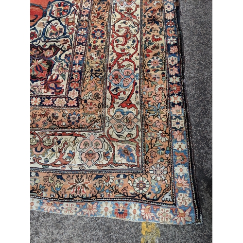 244 - A Persian Heriz hand woven carpet, having a central medallion on a red ground, framed by ivory colou... 