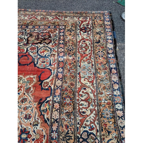 244 - A Persian Heriz hand woven carpet, having a central medallion on a red ground, framed by ivory colou... 