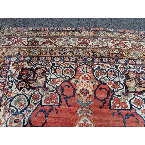 244 - A Persian Heriz hand woven carpet, having a central medallion on a red ground, framed by ivory colou... 