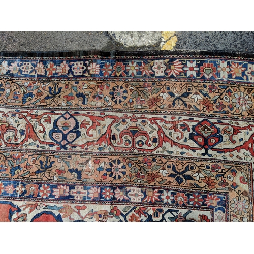 244 - A Persian Heriz hand woven carpet, having a central medallion on a red ground, framed by ivory colou... 