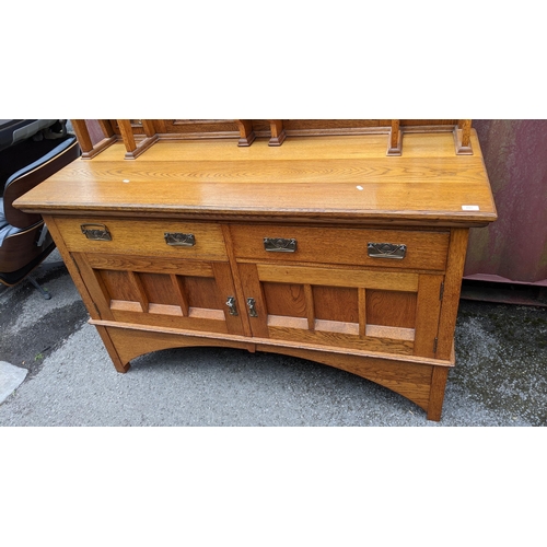 246 - An Arts & Crafts oak mirrored back sideboard, having a moulded flat top pediment above a central mir... 