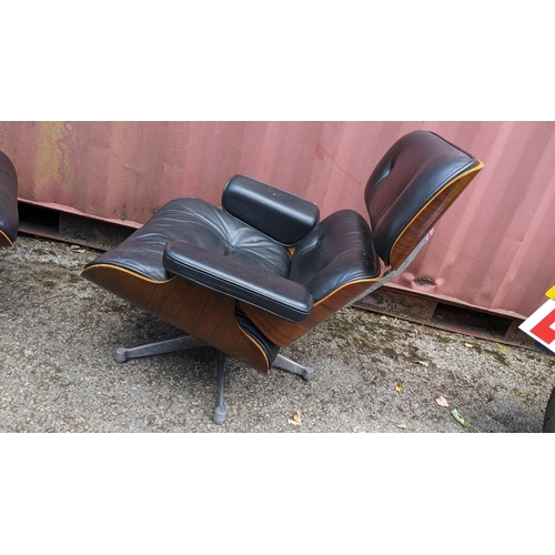 257 - A vintage black leather armchair and ottoman, after the design by Charles and Ray Eames for Herman M... 