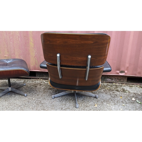 257 - A vintage black leather armchair and ottoman, after the design by Charles and Ray Eames for Herman M... 