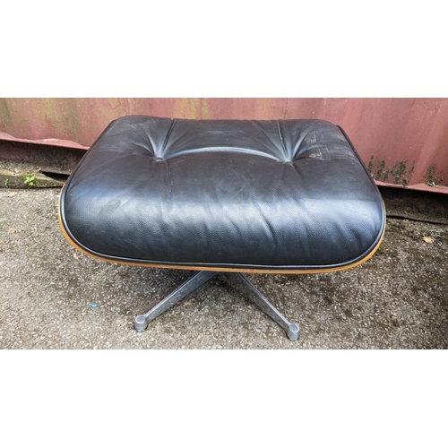 257 - A vintage black leather armchair and ottoman, after the design by Charles and Ray Eames for Herman M... 