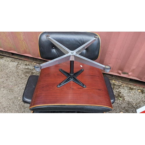 257 - A vintage black leather armchair and ottoman, after the design by Charles and Ray Eames for Herman M... 