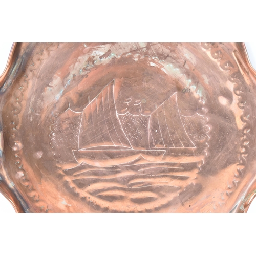 39 - A Newlyn style Arts & Crafts copper tray, having a wavy formed rim and engraved with a sailing boats... 