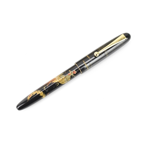 73 - A Namiki fountain pen, with a 14ct yellow gold nib, in black lacquer and relief decorated depicting ... 