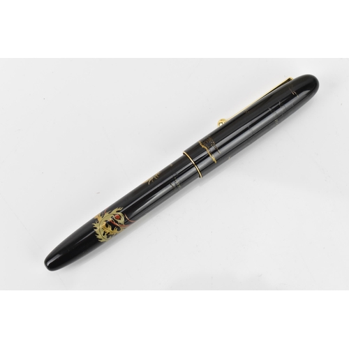 73 - A Namiki fountain pen, with a 14ct yellow gold nib, in black lacquer and relief decorated depicting ... 