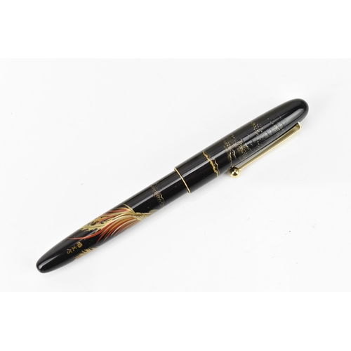 73 - A Namiki fountain pen, with a 14ct yellow gold nib, in black lacquer and relief decorated depicting ... 