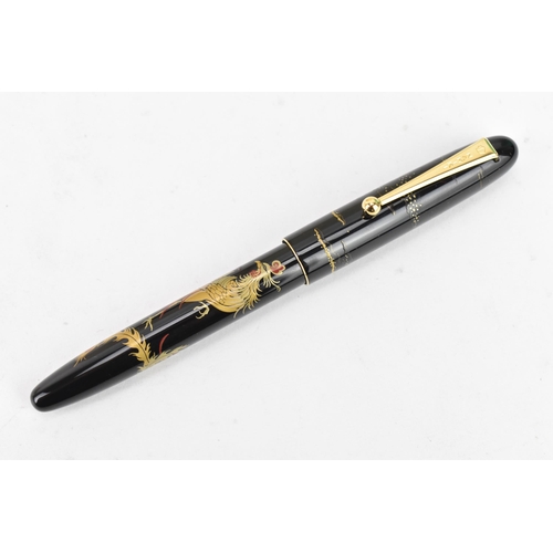 74 - A Namiki fountain pen, with a 14ct yellow gold nib, in black lacquer and relief decorated depicting ... 