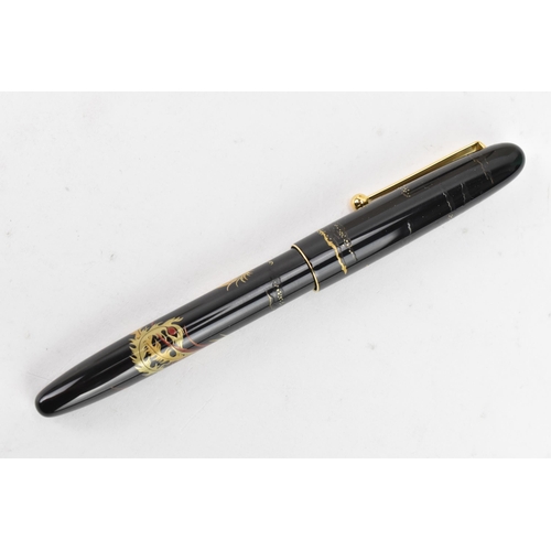 74 - A Namiki fountain pen, with a 14ct yellow gold nib, in black lacquer and relief decorated depicting ... 