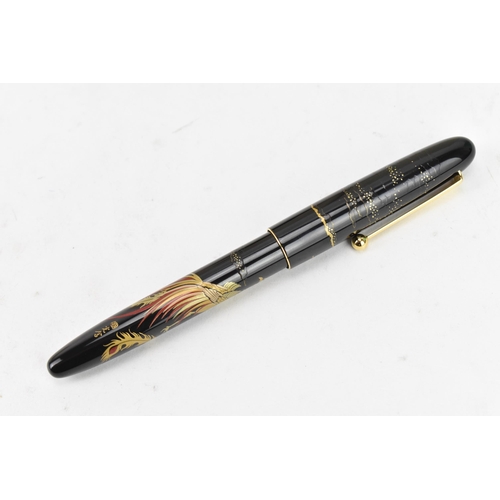 74 - A Namiki fountain pen, with a 14ct yellow gold nib, in black lacquer and relief decorated depicting ... 