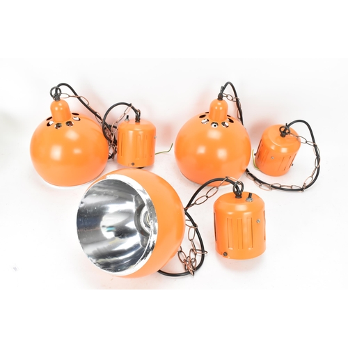 86 - A retro set of three 1970s eyeball hanging lights, each with orange enamel shades and cast iron susp... 