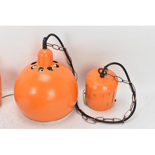 86 - A retro set of three 1970s eyeball hanging lights, each with orange enamel shades and cast iron susp... 