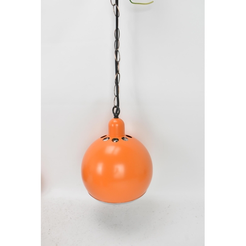 86 - A retro set of three 1970s eyeball hanging lights, each with orange enamel shades and cast iron susp... 