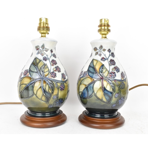 90 - A pair of Moorcroft pottery 'Bramble' pattern table lamps, each of baluster form tube lined with ber... 