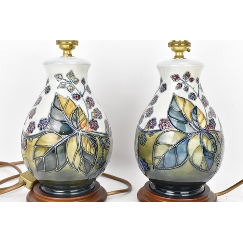 90 - A pair of Moorcroft pottery 'Bramble' pattern table lamps, each of baluster form tube lined with ber... 