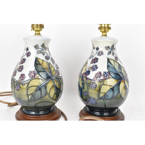 90 - A pair of Moorcroft pottery 'Bramble' pattern table lamps, each of baluster form tube lined with ber... 