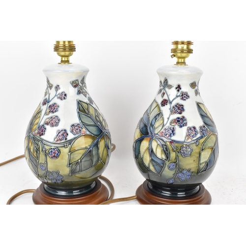 90 - A pair of Moorcroft pottery 'Bramble' pattern table lamps, each of baluster form tube lined with ber... 