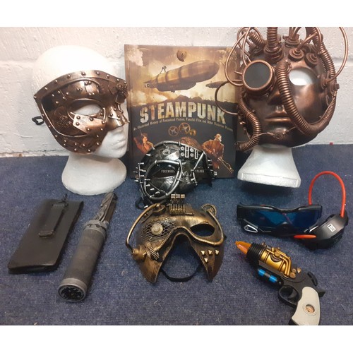 74 - Steampunk interest to include masks, belts, a book and a hat A/F all housed in a vintage green tin w... 