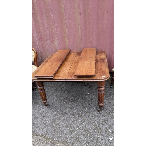 186 - A Victorian mahogany extending dining table, two additional leaves, on turned reeded legs and castor... 