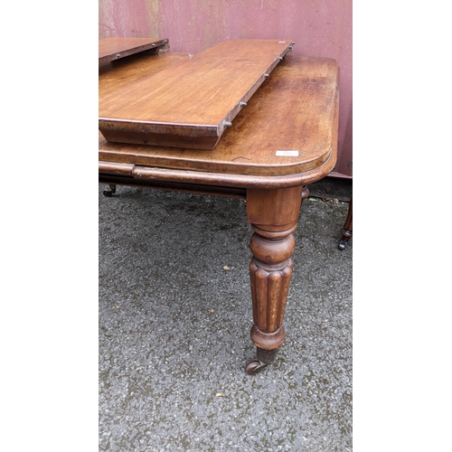 186 - A Victorian mahogany extending dining table, two additional leaves, on turned reeded legs and castor... 