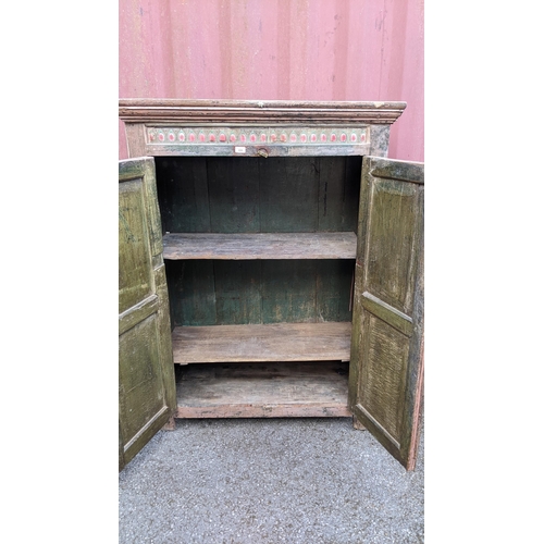 220 - An antique Indian part painted cabinet with a ceramic tile frieze above a pair of panelled doors 148... 