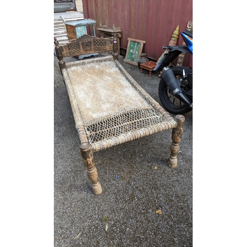 223 - An antique Pakistan hardwood and pine bed with a carved headboard on turned legs Location: Blue Con
... 